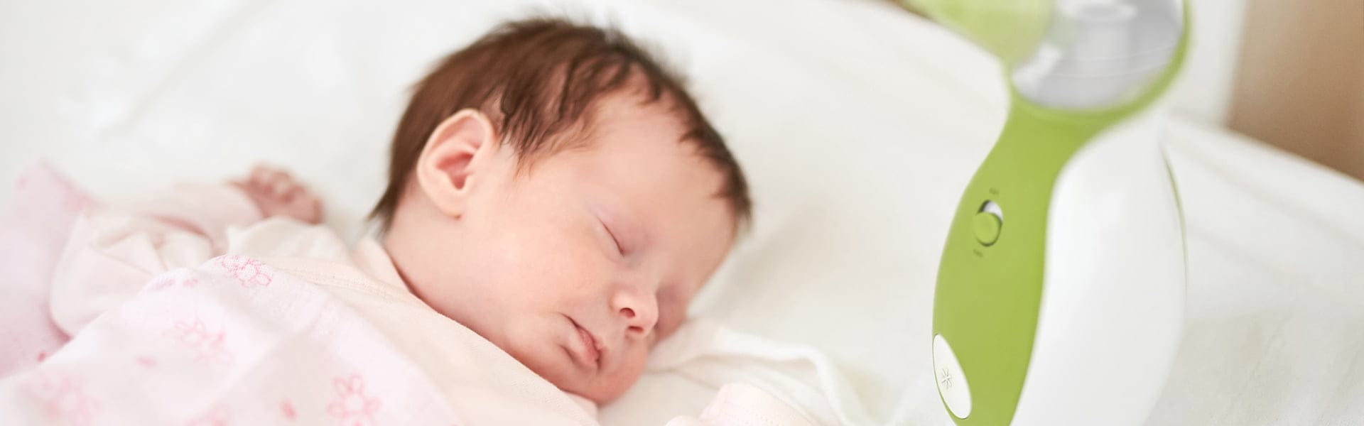 Dziecko śpi spokojnie w łóżeczku, obok przenośny aspirator do nosa Nosiboo Go