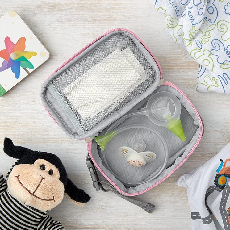 Otwarta kosmetyczka Nosiboo Bag leży na stole, zawiera ustny aspirator do nosa Nosiboo Eco oraz inne akcesoria dla niemowląt
