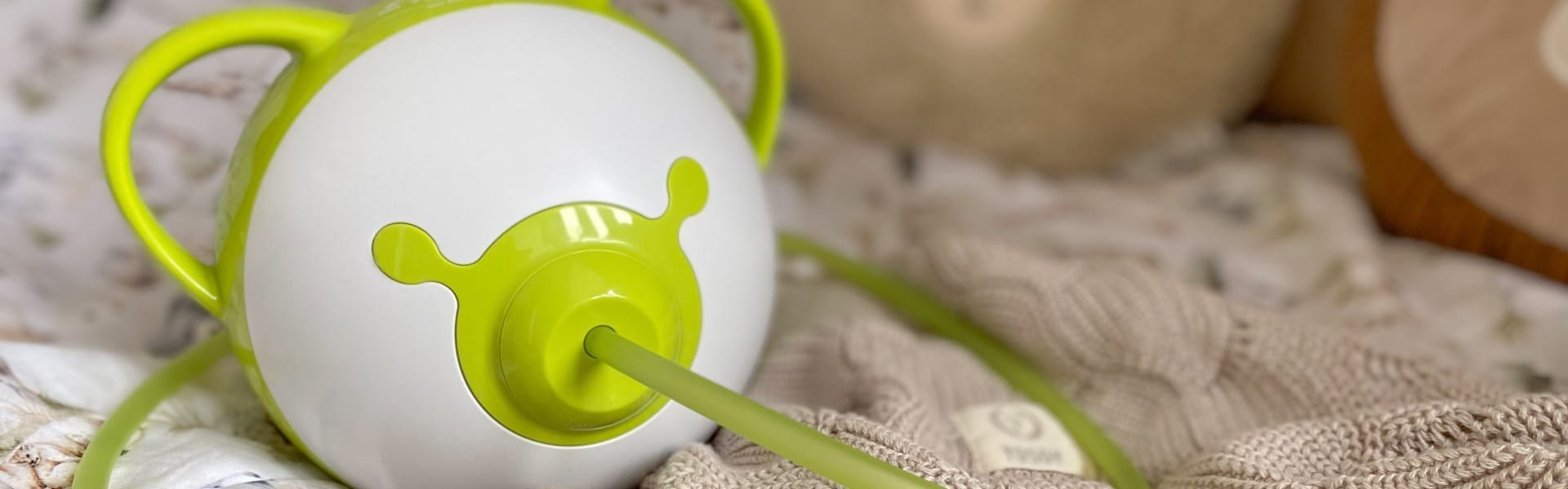 Zielony elektryczny aspirator do nosa Nosiboo Pro2 na łóżku.