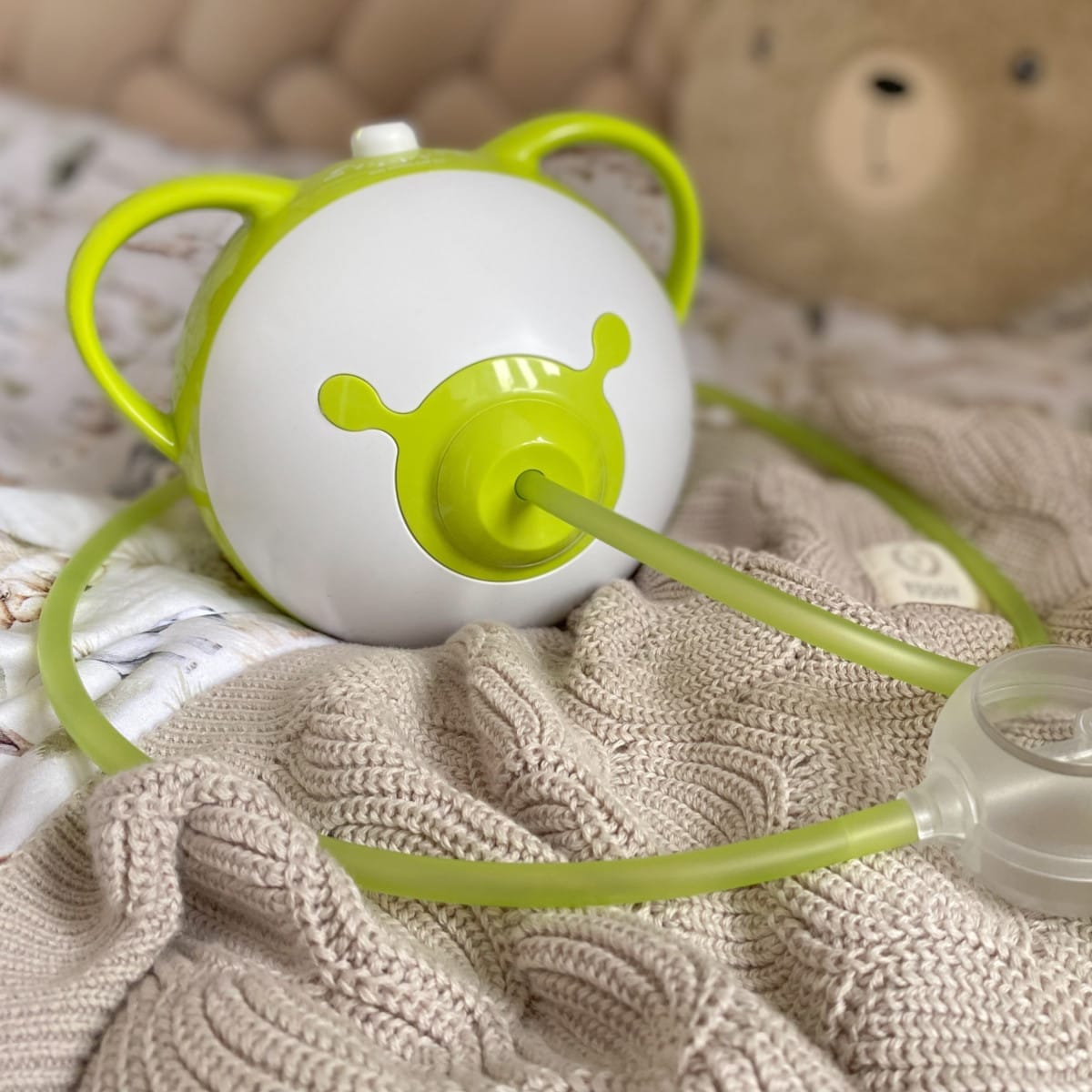 Zielony elektryczny aspirator do nosa Nosiboo Pro2 na łóżku.